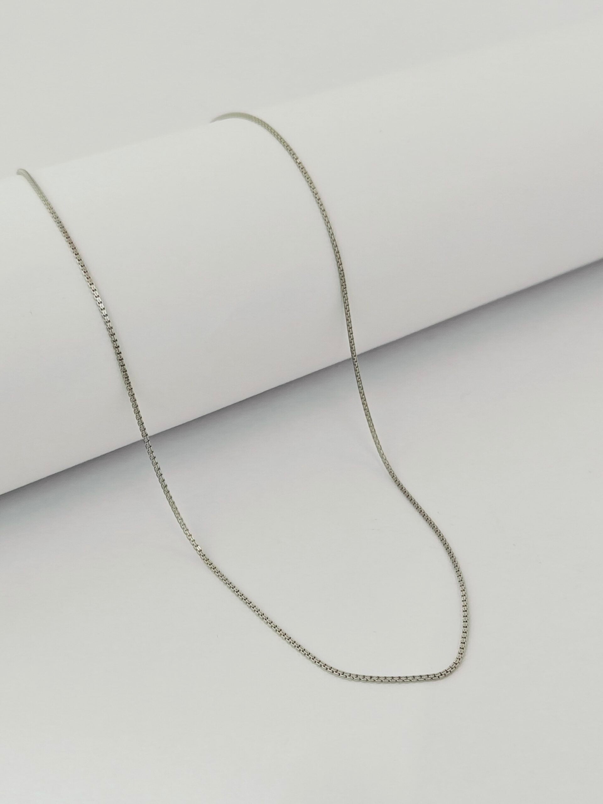Silver chain necklace on a light gray background